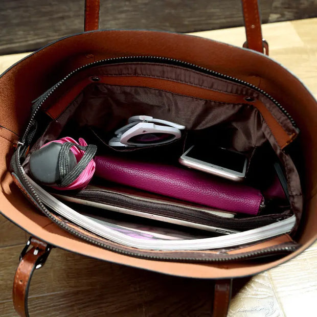 Open brown leather handbag with various items including a purple wallet and phone on a wooden surface.