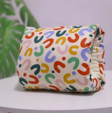 Colorful patterned diaper on a white surface with a blurred green plant in the background