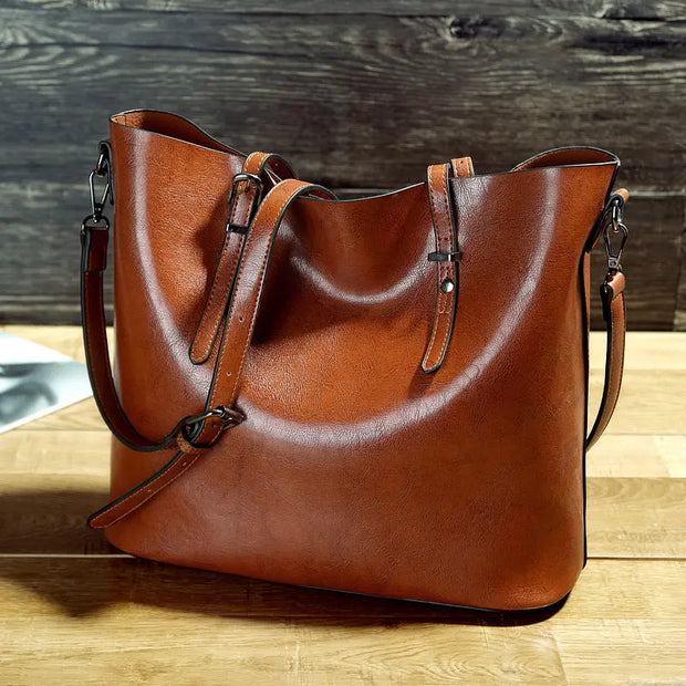 Brown leather handbag on a wooden surface with a wooden background