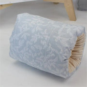 Floral-patterned cylindrical pillow with beige edge on a light gray surface