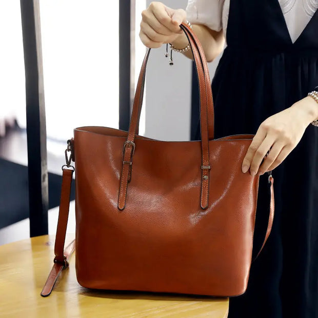 Brown leather handbag held by a person in an indoor setting
