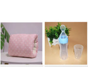 Pink polka dot pillow and clear baby bottle with blue cap on a beige surface.
