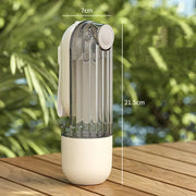 Transparent spray bottle with beige base on a wooden surface, with measurements indicated.