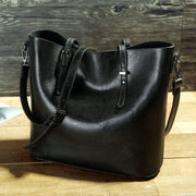 Black leather tote bag on a wooden surface with a wooden background
