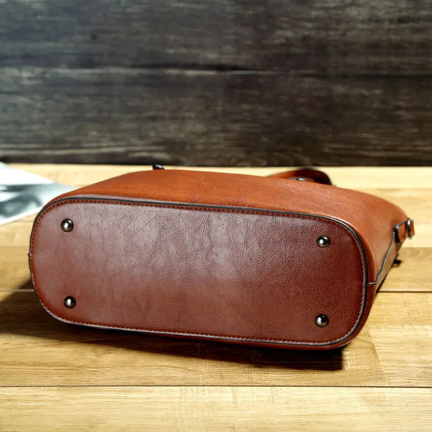 Brown leather bag on a wooden surface with a blurred dark background