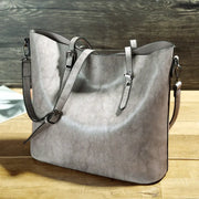 Gray leather handbag on a wooden surface with a wooden background