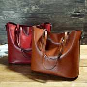 Two leather handbags, one red and one brown, on a wooden surface with a wooden background.
