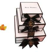 Stack of gift boxes with black ribbons and 'Best Wishes' text on a white background