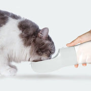 Traveling Out Portable Dog Water Dispenser showing a cat drinking water from a hand-held pet water bottle.