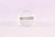 Round white object with a central gray component on a light purple background